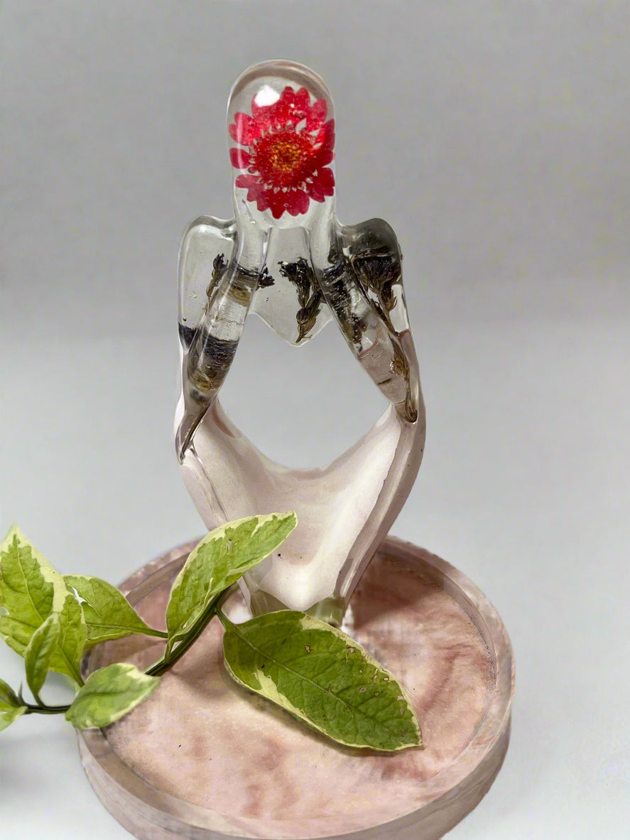Decorative figurine dreamer with a real dried red daisy flower and blue fynbos inside on a pink trinket trey.
