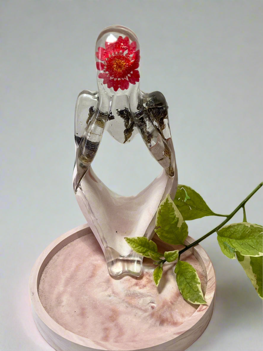Decorative figurine dreamer with a real dried red daisy flower and blue fynbos inside on a pink trinket trey.