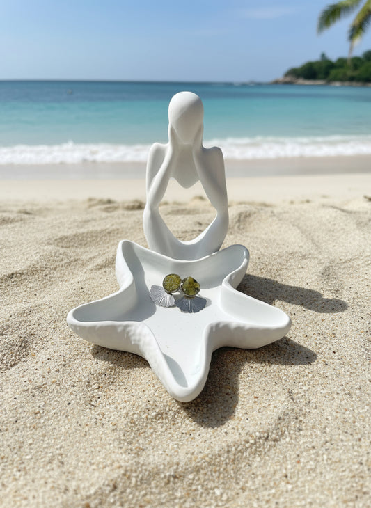 White ceramic starfish-shaped dish with small stones on a beige surface