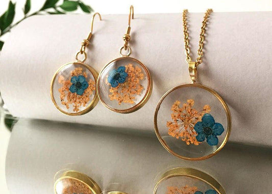 orange blast of wild fynbos flowers with tiny blue flower in a round frame resin earrings necklace gift