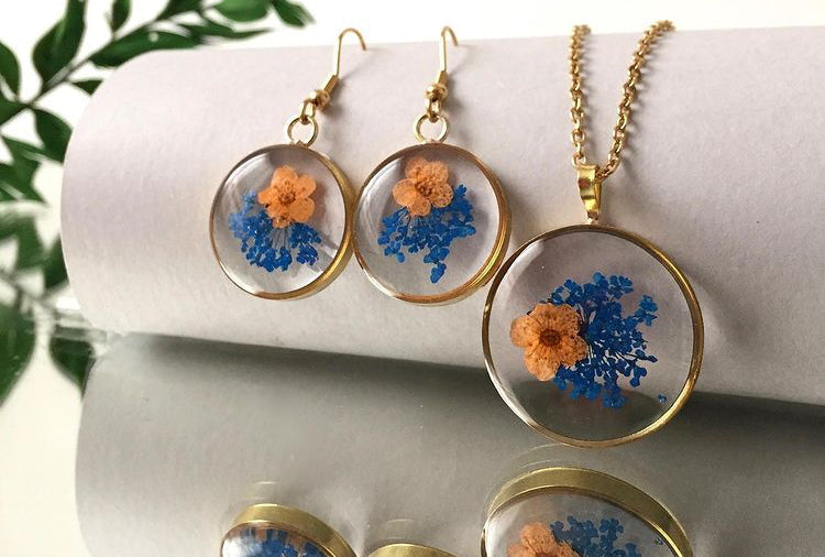 blue blast of wild fynbos flowers with tiny orange flower in a round frame resin earrings necklace gift